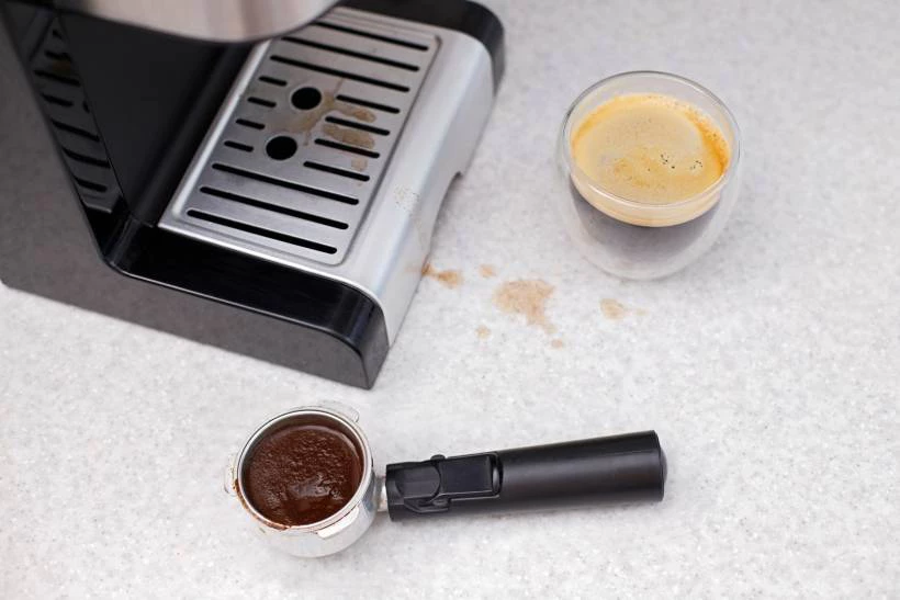 Breville Barista Pro espresso machine being cleaned with a microfiber cloth, steam wand purging, and cleaning tablet placed in blind filter, step-by-step maintenance guide