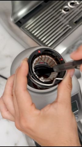 Open Breville coffee grinder showing 40mm stainless steel conical burrs, wire handle, and felt washer after thorough cleaning with brush and vacuum.