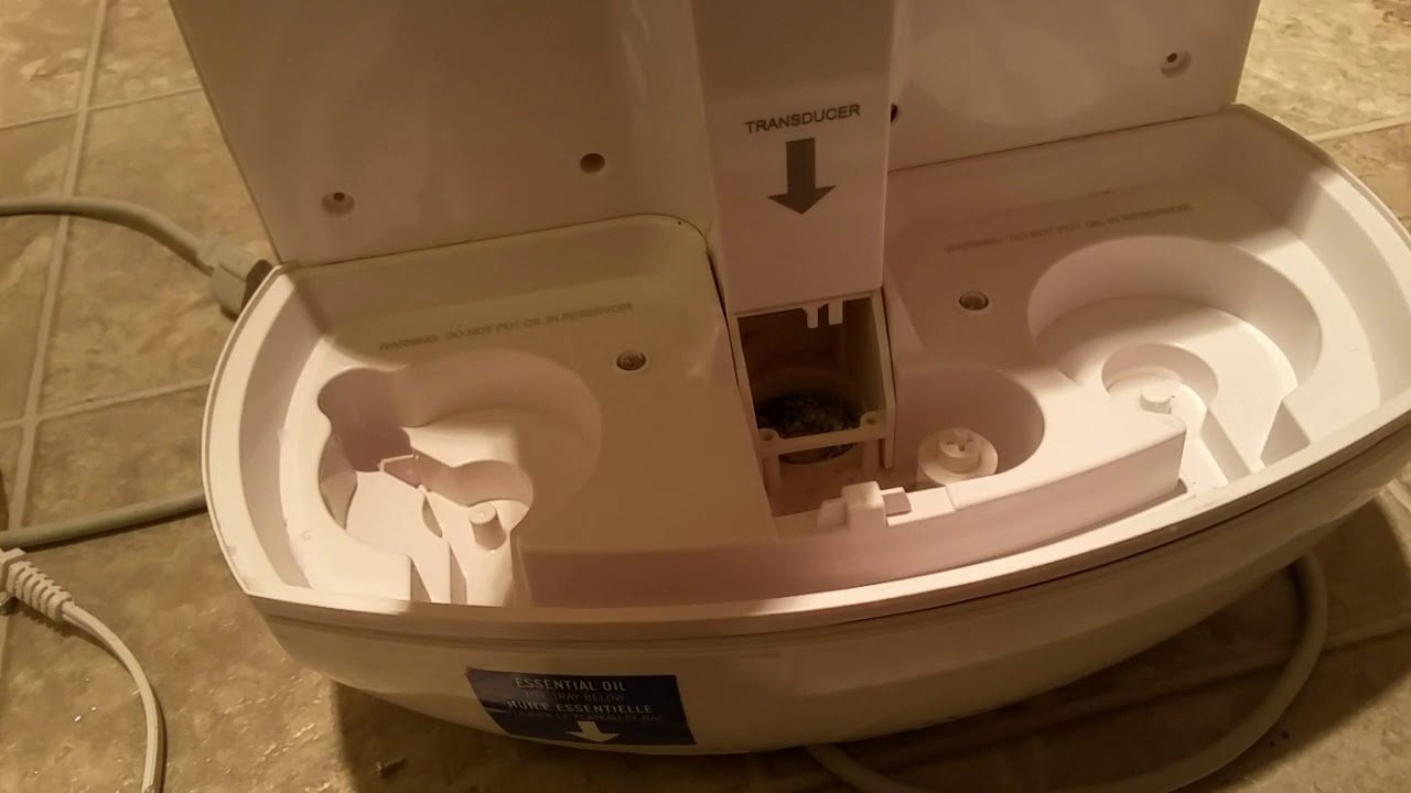 Hands cleaning a HoMedics ultrasonic humidifier base with white vinegar solution and soft cloth