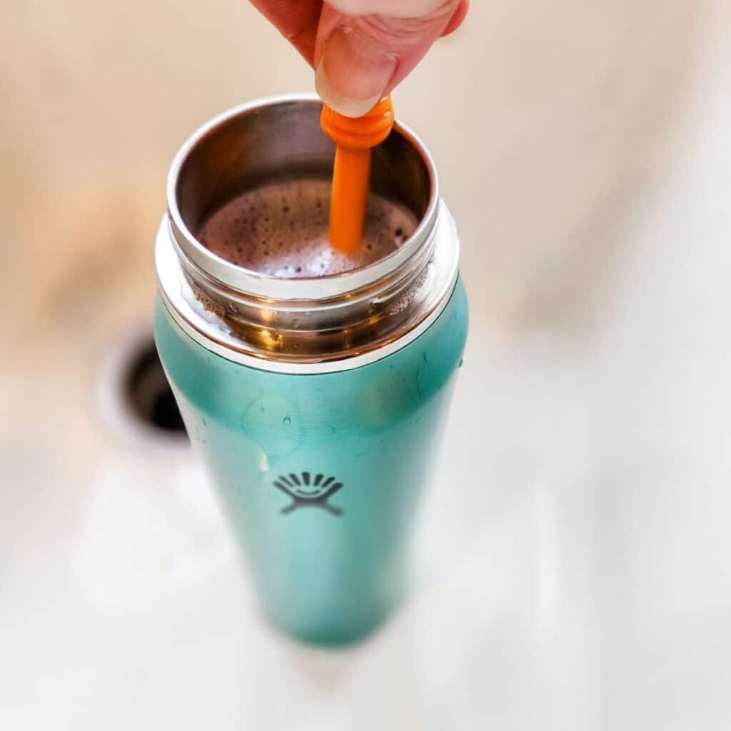 Step-by-step visual guide to cleaning a Hydro Flask lid with vinegar soak, toothpick gasket scrubbing, and air drying process.