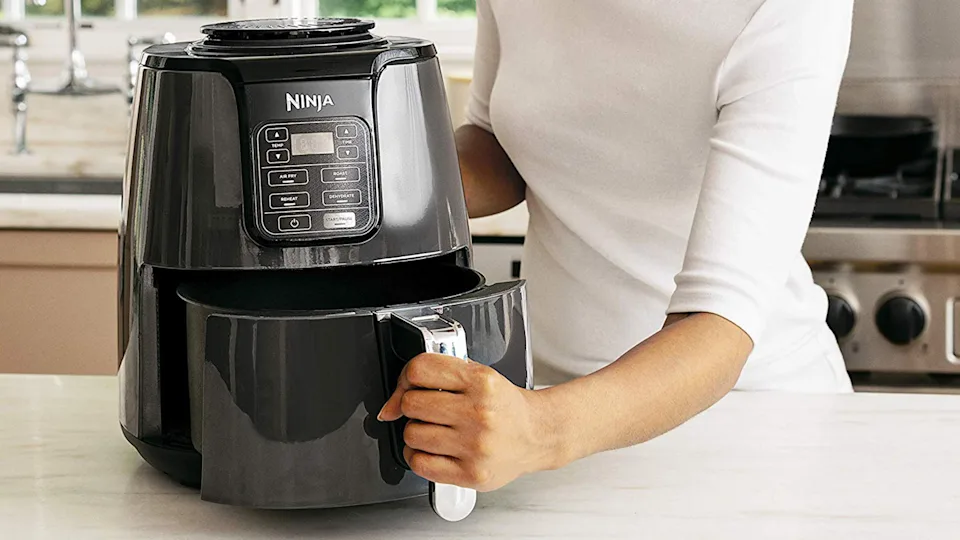 Step by step cleaning a Ninja air fryer heating element with soft brush, Dawn spray, and baking soda paste on a kitchen counter.