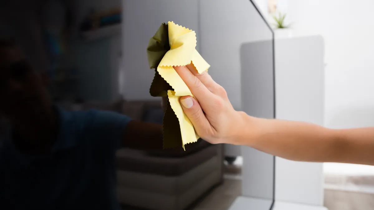 A Nintendo Switch being carefully cleaned with a microfiber cloth, showcasing screen, vents, and Joy-Con maintenance without damage.