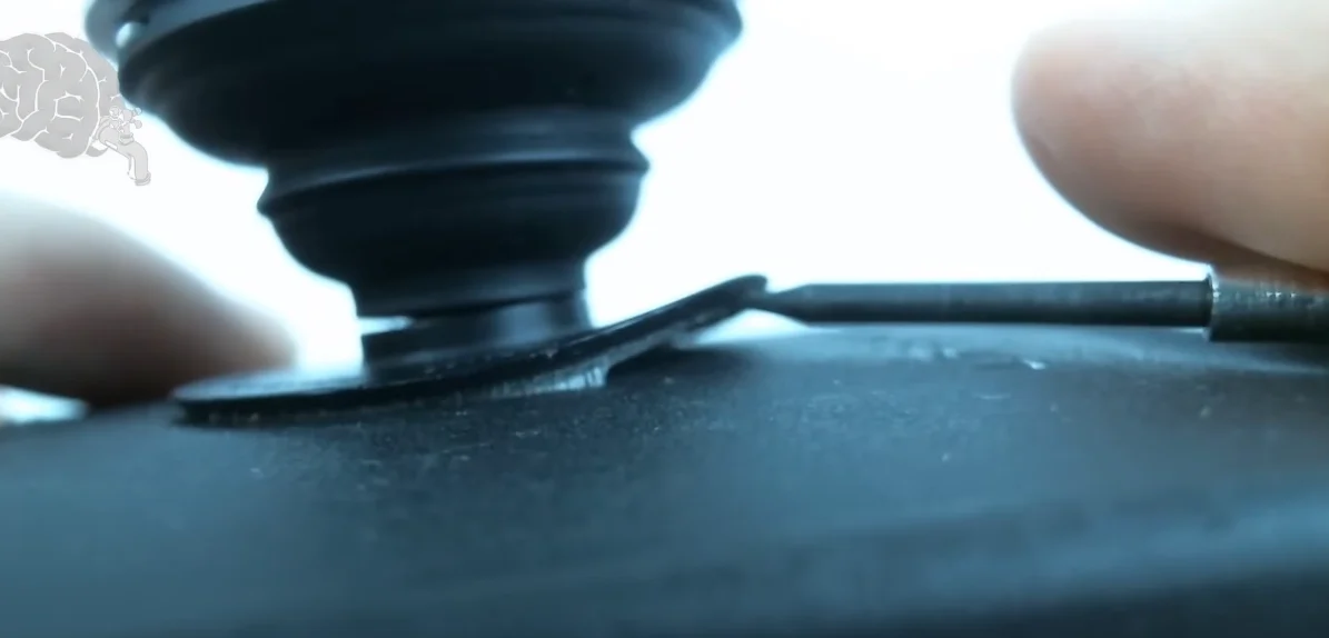 Clean PopSocket adhesive gel being rinsed under lukewarm water with timer showing 10-minute drying countdown on wooden table